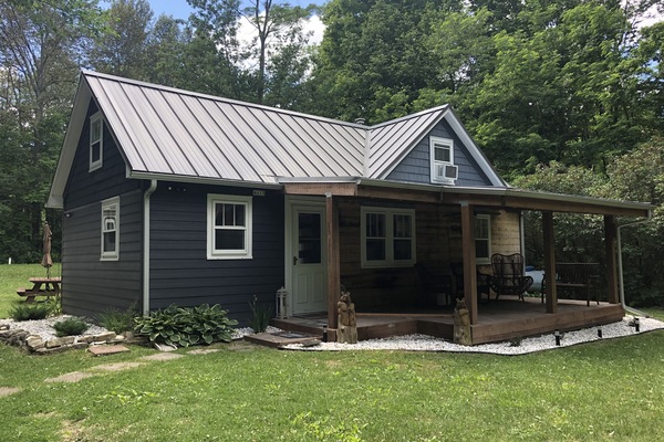 Front of the cottage. Porch has furniture, a ceiling fan, and metal roof.