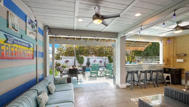 A covered patio area with a sofa, dining table, chairs, and a bar area. - Bay 2 Bay: Bay Across Street! Amazing Views of Bay & Canal, Pool & Lounge by Anna Maria Life (Anna Maria)