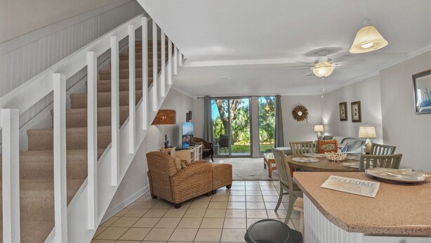 A spacious living area with a staircase, a sofa, a dining table, and a kitchen counter.