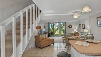 A spacious living area with a staircase, a sofa, a dining table, and a kitchen counter.