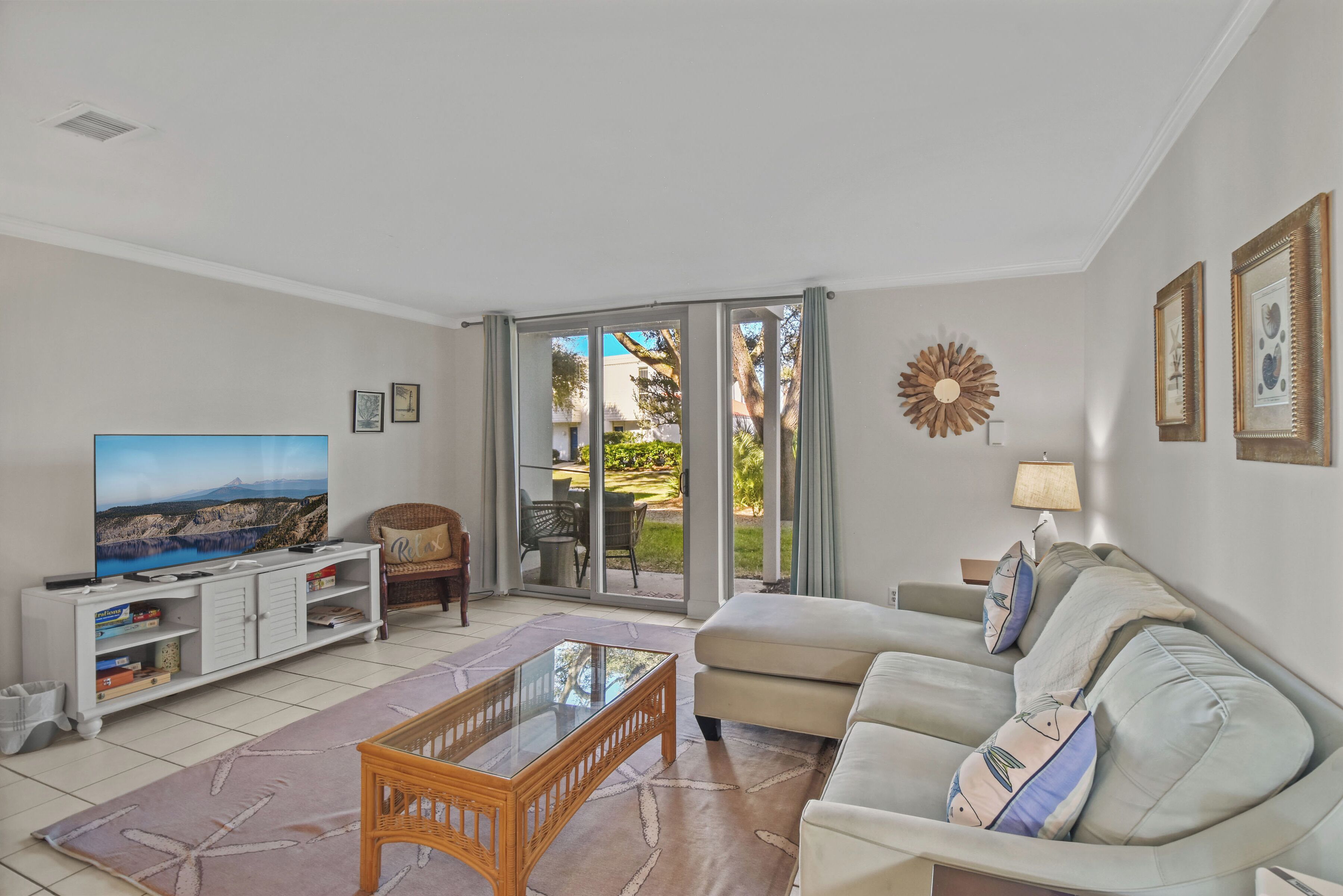 A living room with a sofa, TV, entertainment unit, and a view through a glass door.
