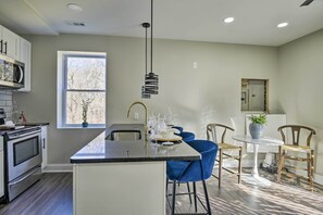 Una cocina moderna con una isla central, electrodomésticos de acero inoxidable y taburetes de bar azules.