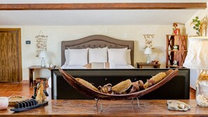 A bedroom with a bed, wooden headboard, bedside tables, and a wooden boat-shaped object on the table. - Villa TreA - Loft Alba (Mascali)