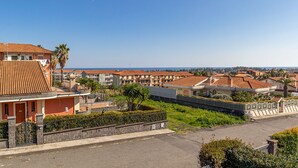 A residential area with terracotta-roofed houses, a paved road, and a clear blue sky. - Villa TreA - Loft Alba (Mascali)