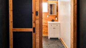A wooden interior with a sliding door, a white sink, and a mirror. - Fish Cabin at the Pines - Lake O' the Pines - Hot Tub - Fire Pit (Jefferson)