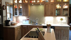 Une cuisine avec des meubles en bois, un îlot central et un luminaire suspendu.