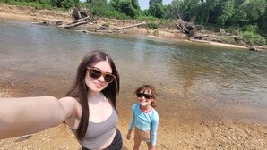 Une personne prend un autoportrait sur la rive d’une rivière.