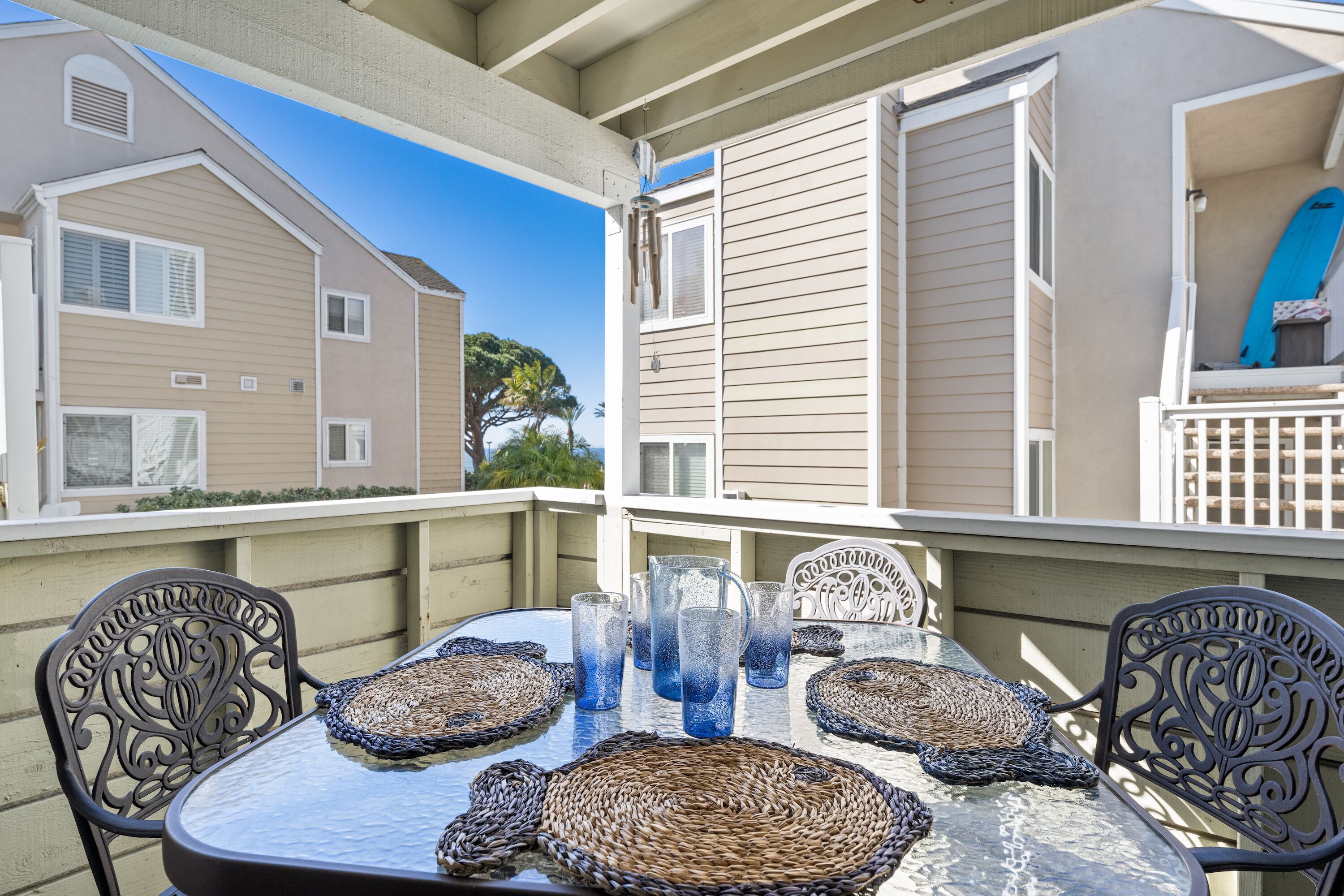 A balcony with a table set for four, surrounded by wicker placemats and clear glassware.