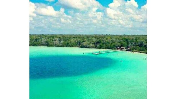 A coastal view with clear turquoise waters, a pier, and a forested area. - Rouse's House near Hotel Zone, Zamna Fest (Tulum)