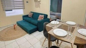 A compact living space with a sofa, a dining table set for two, and a small rug. - Rouse's House near Hotel Zone, Zamna Fest (Tulum)