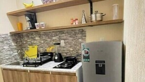 A compact kitchen with a refrigerator, a stove, and a microwave. There are wooden cabinets and a stone backsplash. - Rouse's House near Hotel Zone, Zamna Fest (Tulum)