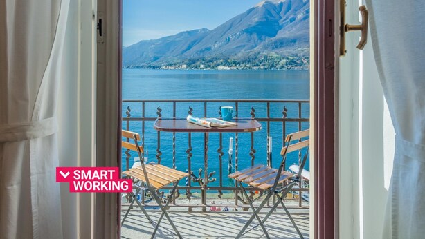 A balcony with a table and chairs overlooking a lake and mountains. - Casa Cavour by Wonderful Italy (Bellagio)