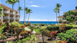 Un resort con vista al océano, palmeras y un jardín bien cuidado.