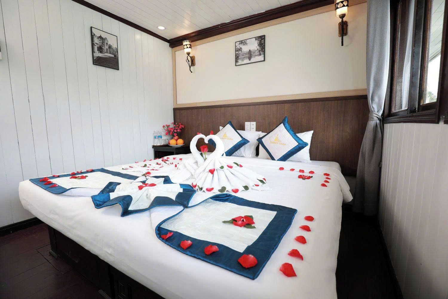 Ein Hotelzimmer mit einem ordentlich bezogenen Bett, einem Nachttisch mit Blumenvase und zwei gerahmten Bildern an der Wand.