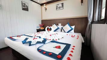 Ein Hotelzimmer mit einem ordentlich bezogenen Bett, einem Nachttisch mit Blumenvase und zwei gerahmten Bildern an der Wand.