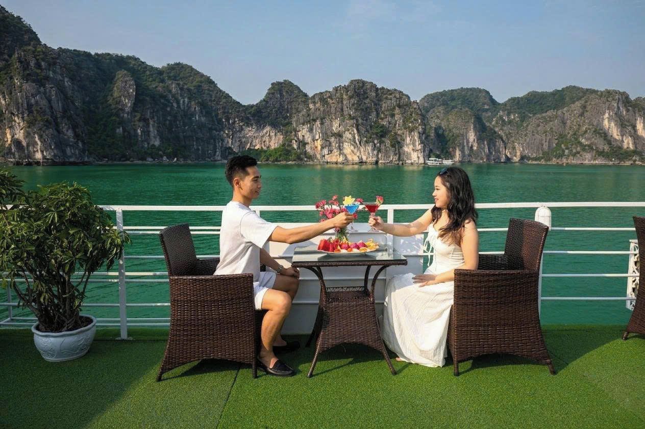 A couple dining at a table with a view of a mountainous coastline.