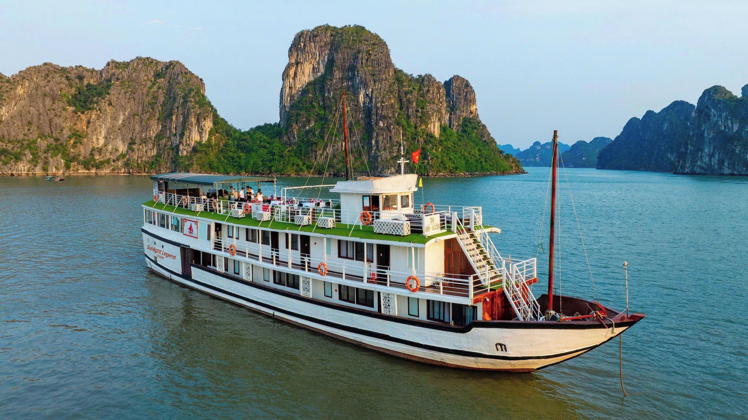 Ein großes Flusskreuzfahrtschiff mit mehreren Decks und einer überdachten oberen Ebene, umgeben von Felsen und Wasser.