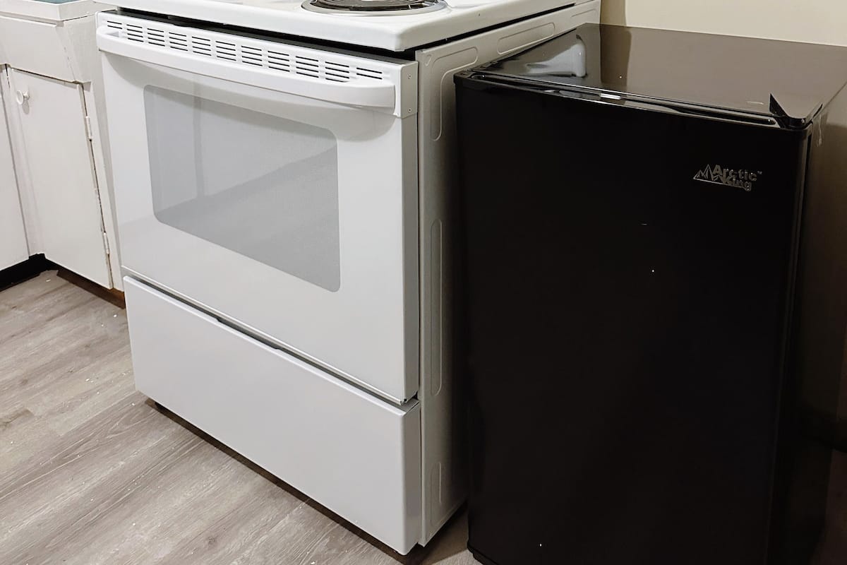 Une cuisine avec un four blanc, un réfrigérateur noir et un four à micro-ondes.