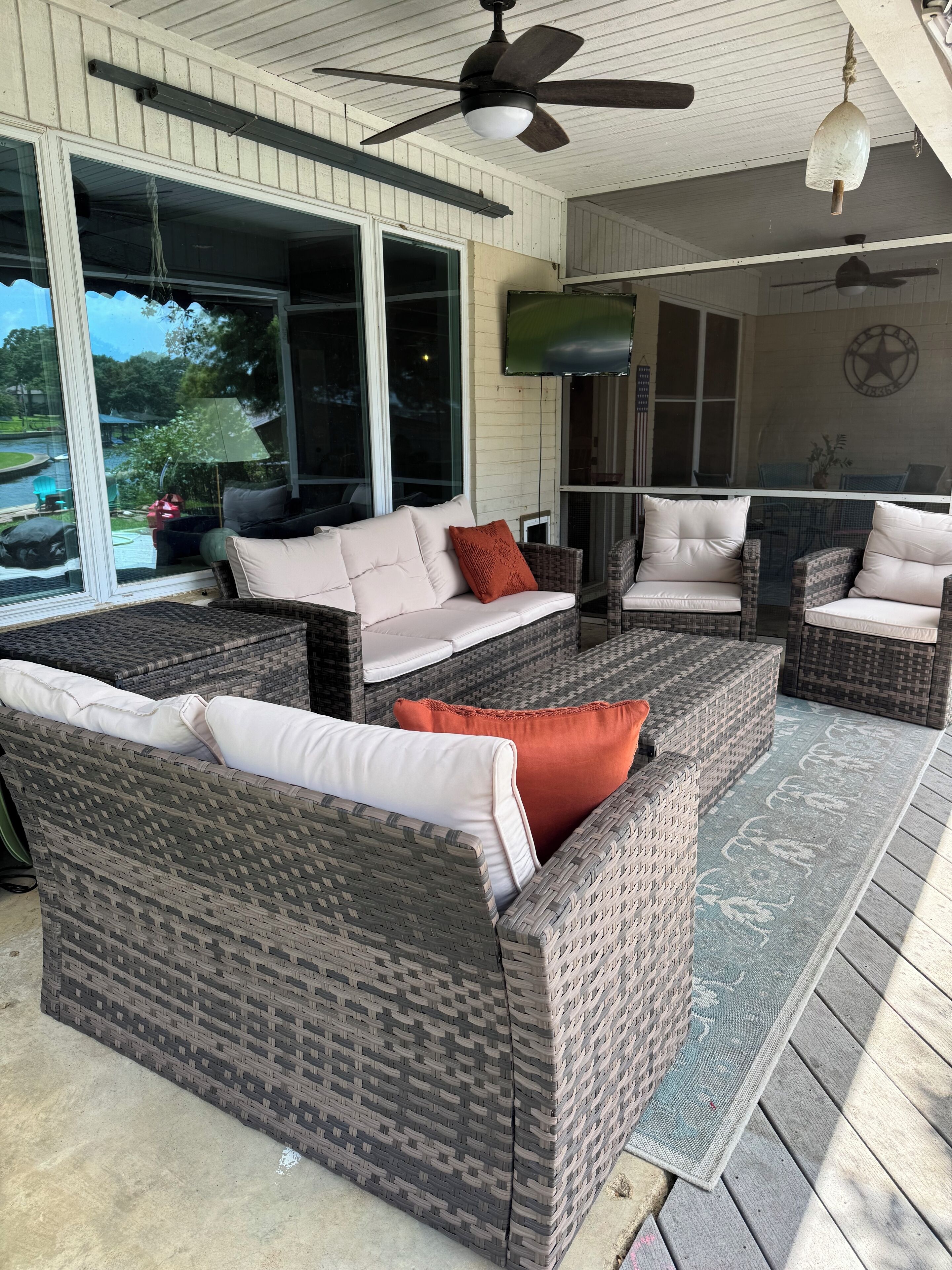 A covered outdoor seating area with wicker furniture and a view of the outdoors.