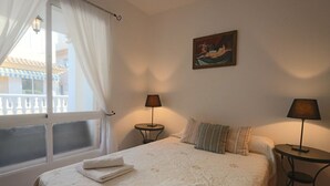 Hotellihuone, jossa on sänky, kaksi yöpöytää, ikkuna verhoilla ja taulu seinällä.