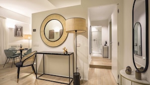 A modern living room with a dining area, a large round mirror, and a floor lamp.