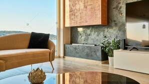 Un salon moderne avec un canapé en cuir, une table basse en verre, un téléviseur à écran plat et une vue sur la mer.