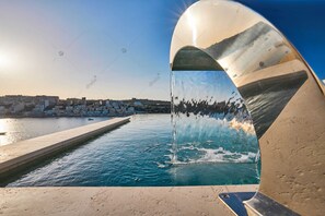 A modern water feature with a clear view of a coastal town in the background. - Luxury House With Pool (St. Paul's Bay)
