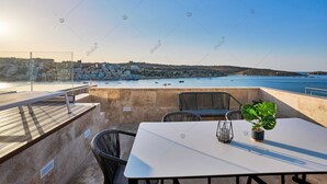 Une terrasse avec une table et des chaises donnant sur une ville côtière.
