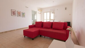 Ein geräumiges Wohnzimmer mit einem roten Ecksofa, einem weißen Couchtisch und einer Vase mit Blumen.