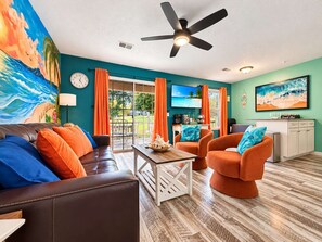 A room with a ceiling fan, a sofa, two armchairs, a coffee table, and a television.