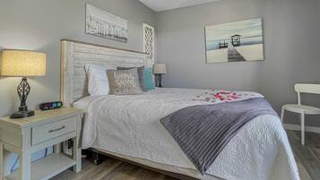 A bedroom with a bed, nightstand, lamp, and wall art.
