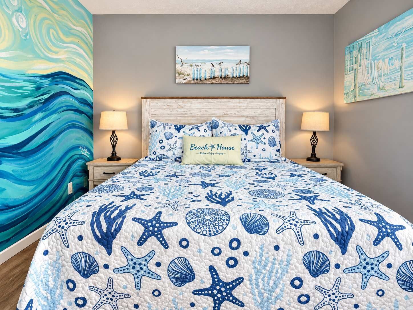 A bedroom with a bed, two bedside lamps, a headboard, and a wall with a painting.