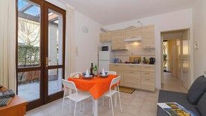 Eine moderne Küche mit Holzausstattung, einem Essbereich mit Tisch und Stühlen sowie Blick durch eine Glastür.