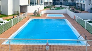 A swimming pool with a tiled deck, surrounded by a white fence, and adjacent to a multi-story residential building with balconies. - Payen Corralejo by Best Holidays Fuerteventura (Corralejo)