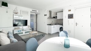 A modern, compact living space with a dining area, kitchenette, and a TV in the living room. - Payen Corralejo by Best Holidays Fuerteventura (Corralejo)