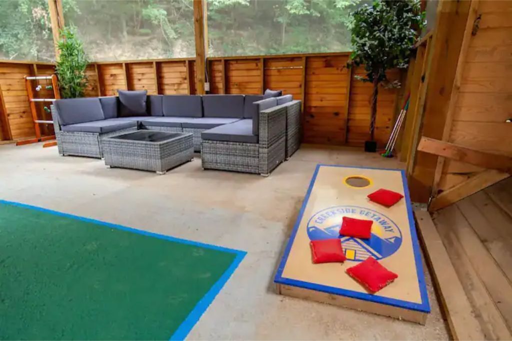 A wooden deck with a sectional sofa and a board game table.