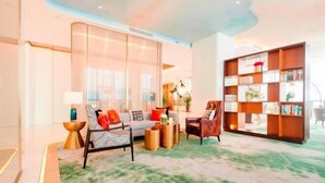 A modern living room with a sofa, armchairs, a bookshelf, and a decorative floor lamp. - Oriental Cobure Hotel (Weifang)