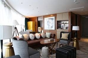 A modern hotel room with a curved seating area, a round table, and a kitchenette. - Oriental Cobure Hotel (Weifang)