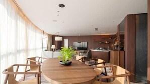 A modern dining area with a round table, wooden chairs, and a potted plant. - Oriental Cobure Hotel (Weifang)