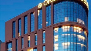 A modern building with a curved glass facade and the sign "ORIENTAL COBBL". - Oriental Cobure Hotel (Weifang)