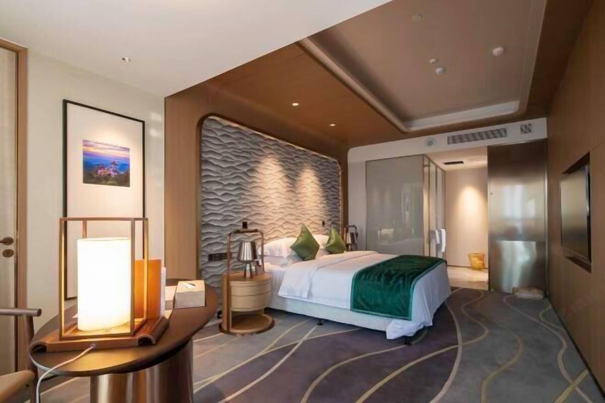 Ein modernes Hotelzimmer mit einem Bett, einem Nachttisch, einer Lampe und einem Wandbild.
