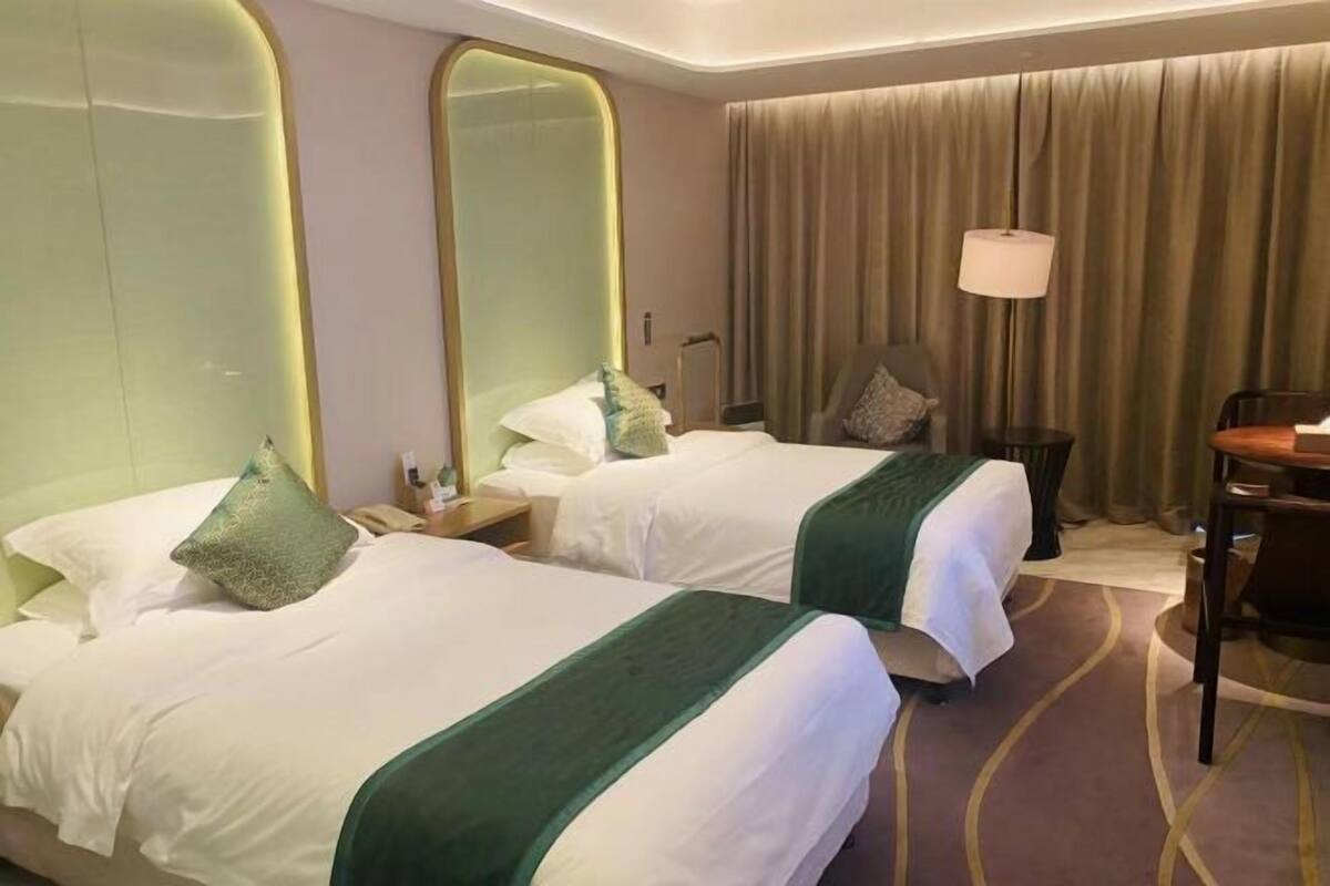 Ein Hotelzimmer mit zwei Betten, einem großen Spiegel, einem Schreibtisch und einem Stuhl.