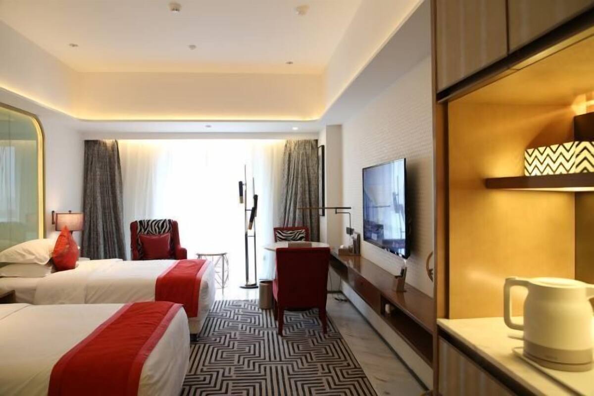 Ein Hotelzimmer mit zwei Betten, einem Fernseher, einer Kaffeemaschine und einem Schreibtisch mit Stuhl.