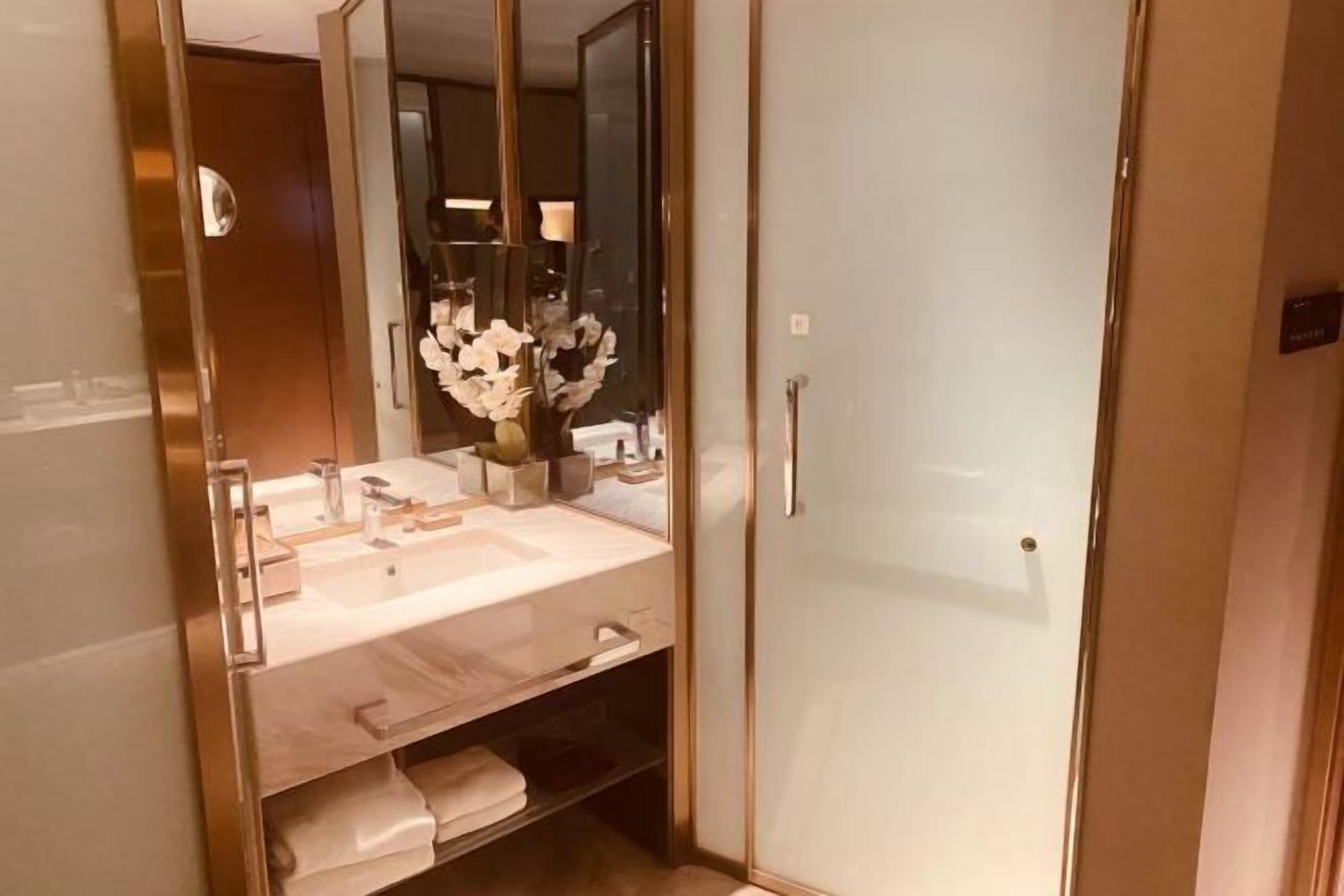 A modern bathroom with a glass-enclosed shower, a vanity with a mirror, and a vase with white flowers.