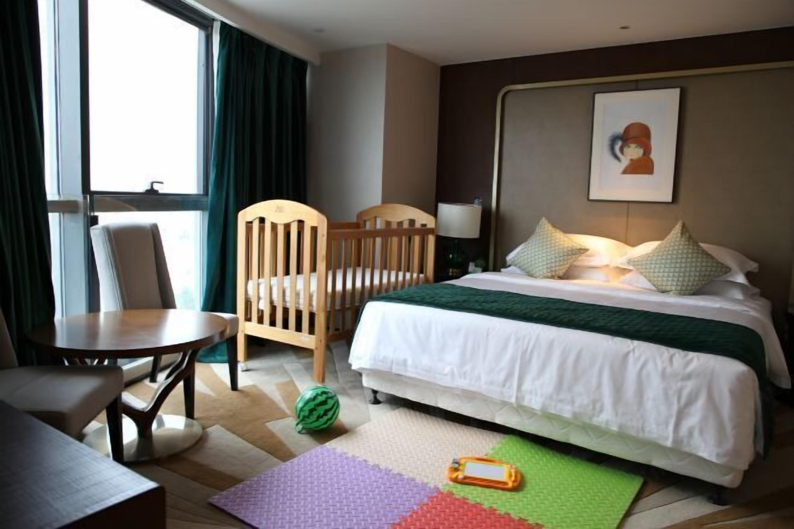A hotel room with a bed, a chair, a table, and a view of the outdoors.