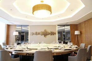 A conference room with a round table, chairs, a chandelier, and a wall art piece. - Oriental Cobure Hotel (Weifang)