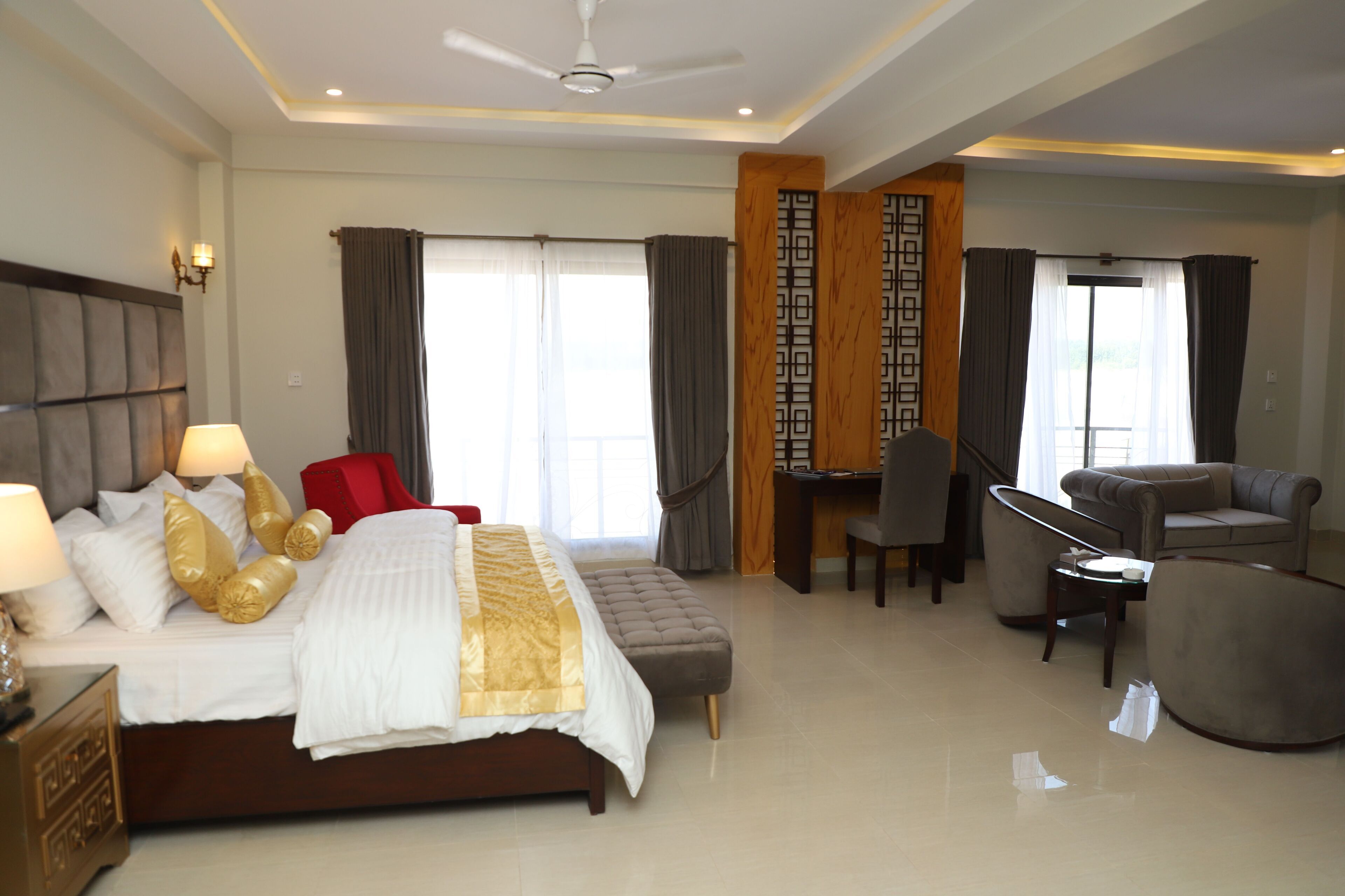 A hotel room with a bed, a desk, a chair, and a sofa.