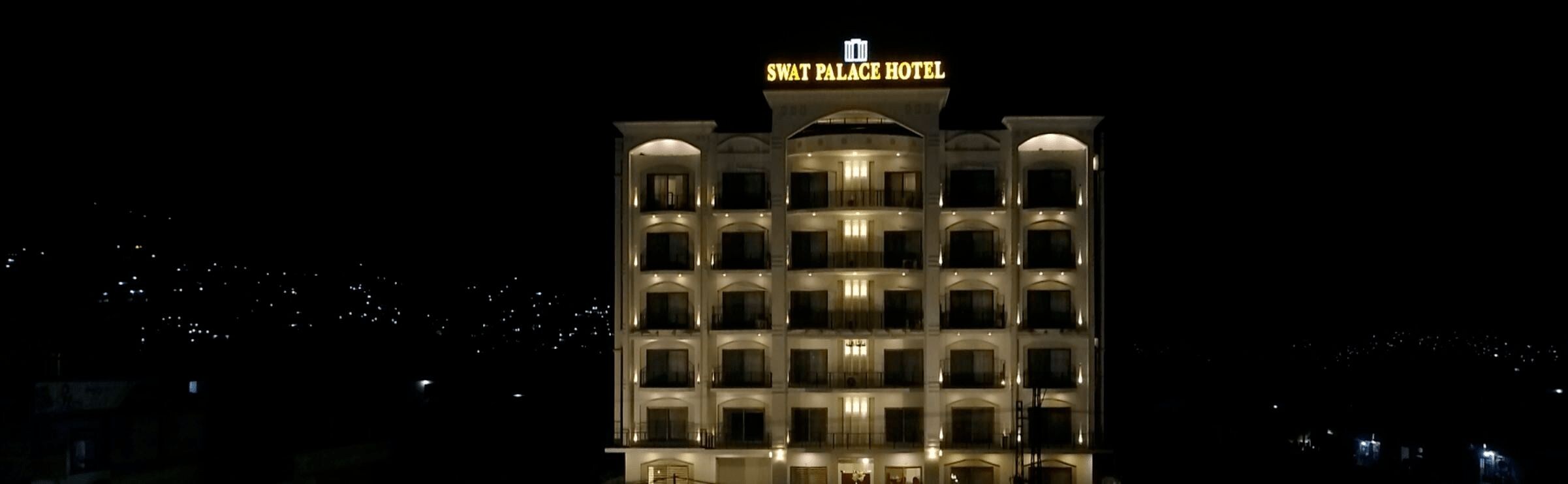 A multi-story hotel with illuminated signage reading "SWAT PALACE HOTEL".
