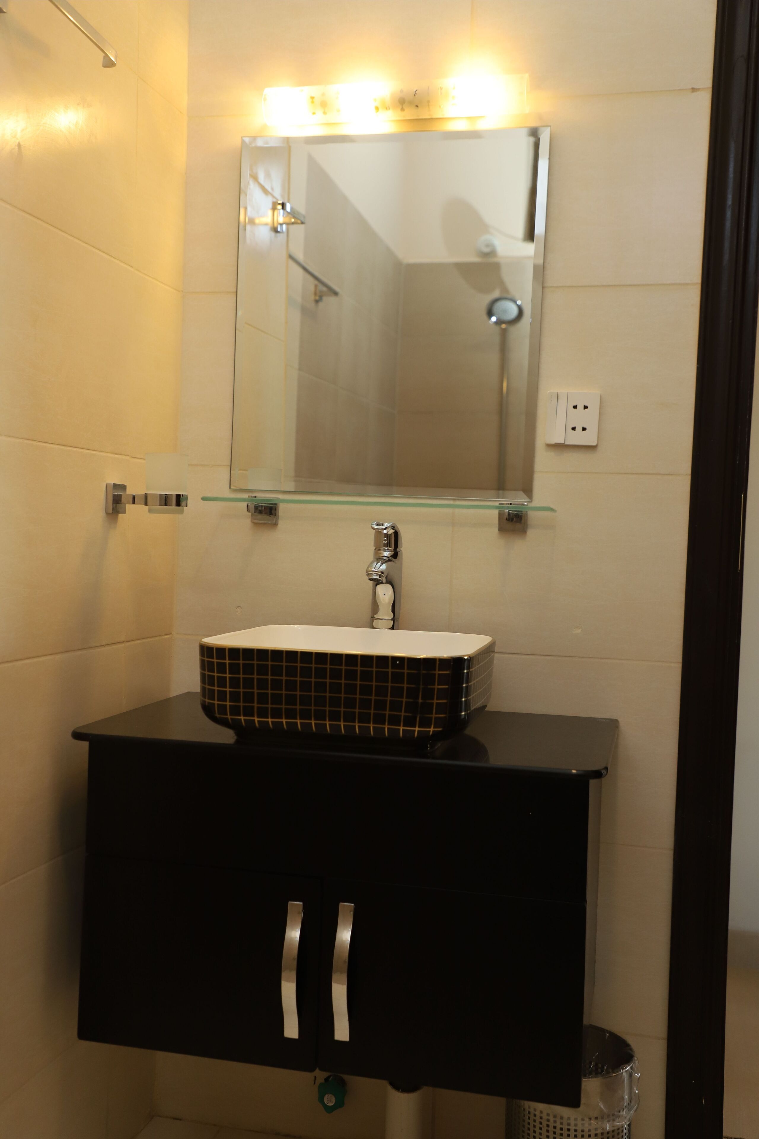 A bathroom with a glass shelf above a sink, a mirror, and a shower.