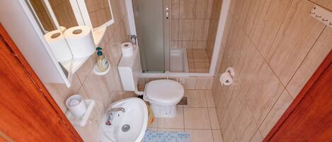 Un baño pequeño con inodoro, lavabo y ducha.